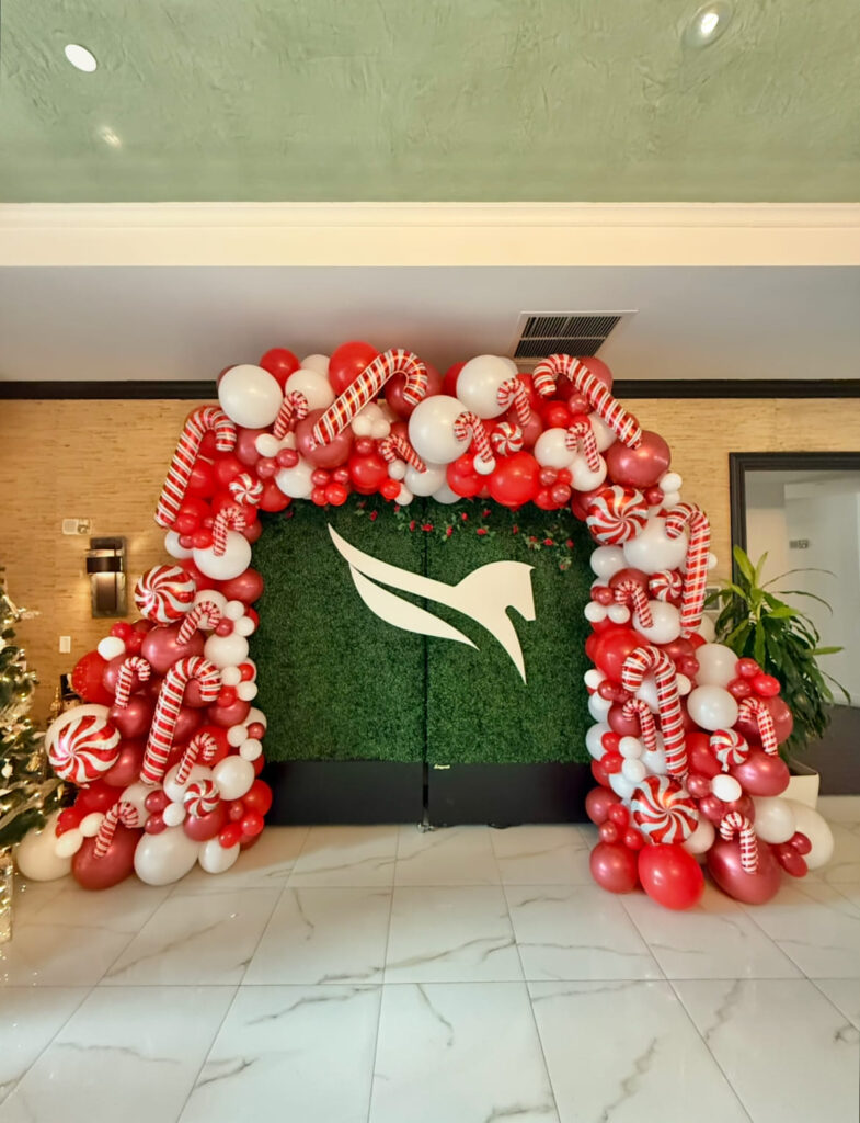 Red and white balloon garland around a holiday photo backdrop