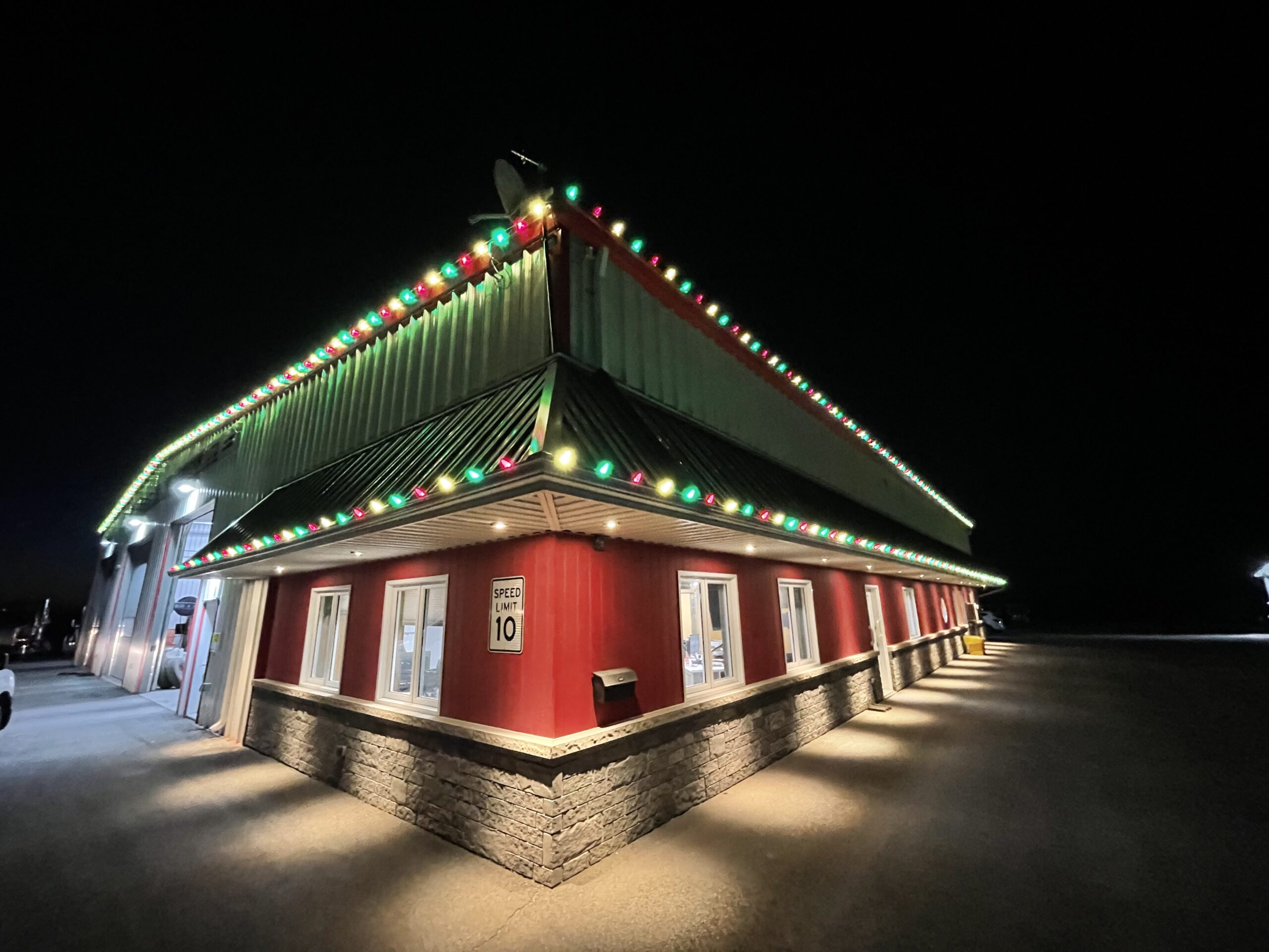 Commercial building with red and green holiday lights along the roof edge