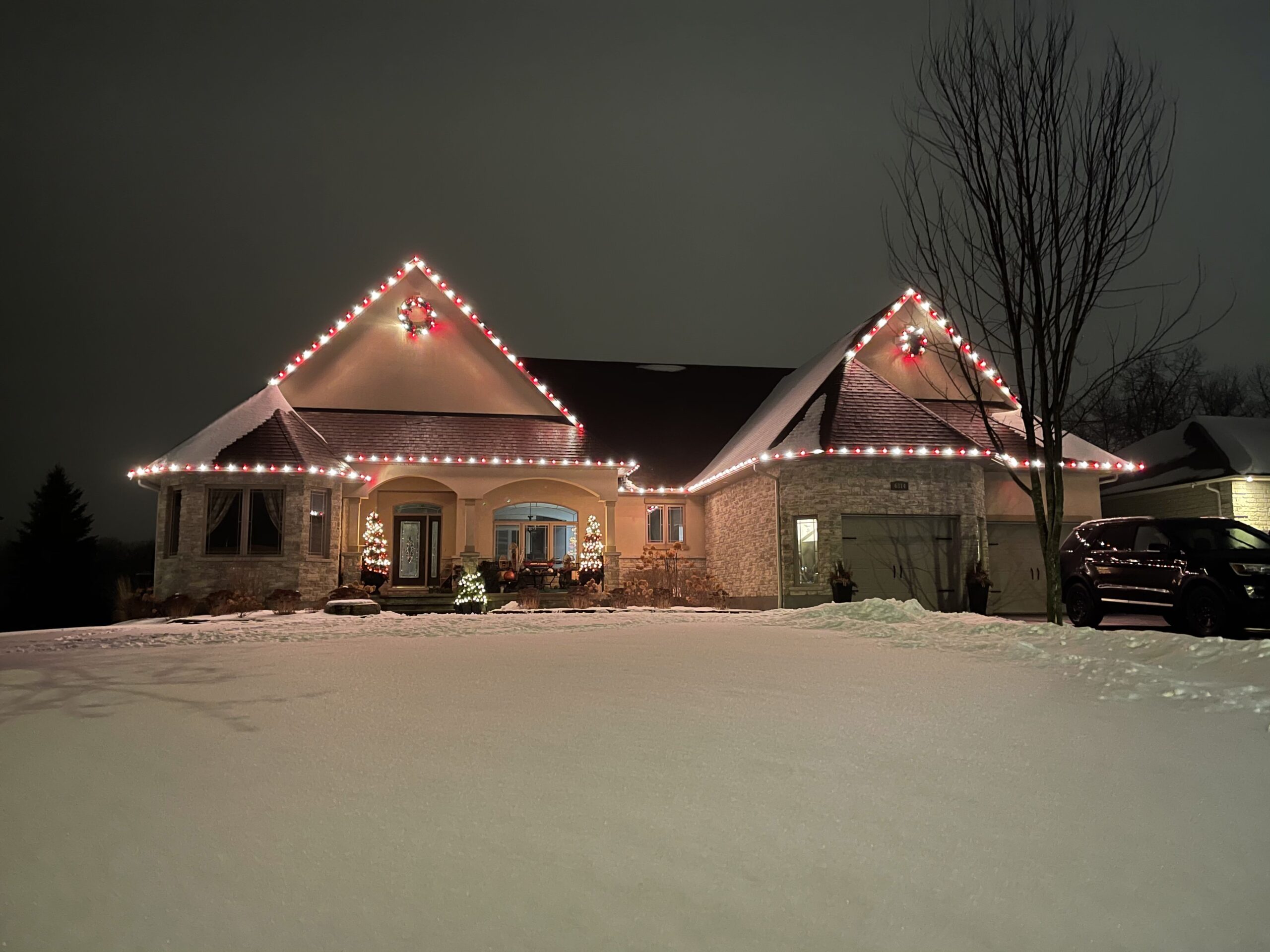 Brick home with red and white Christmas lights across the roofline