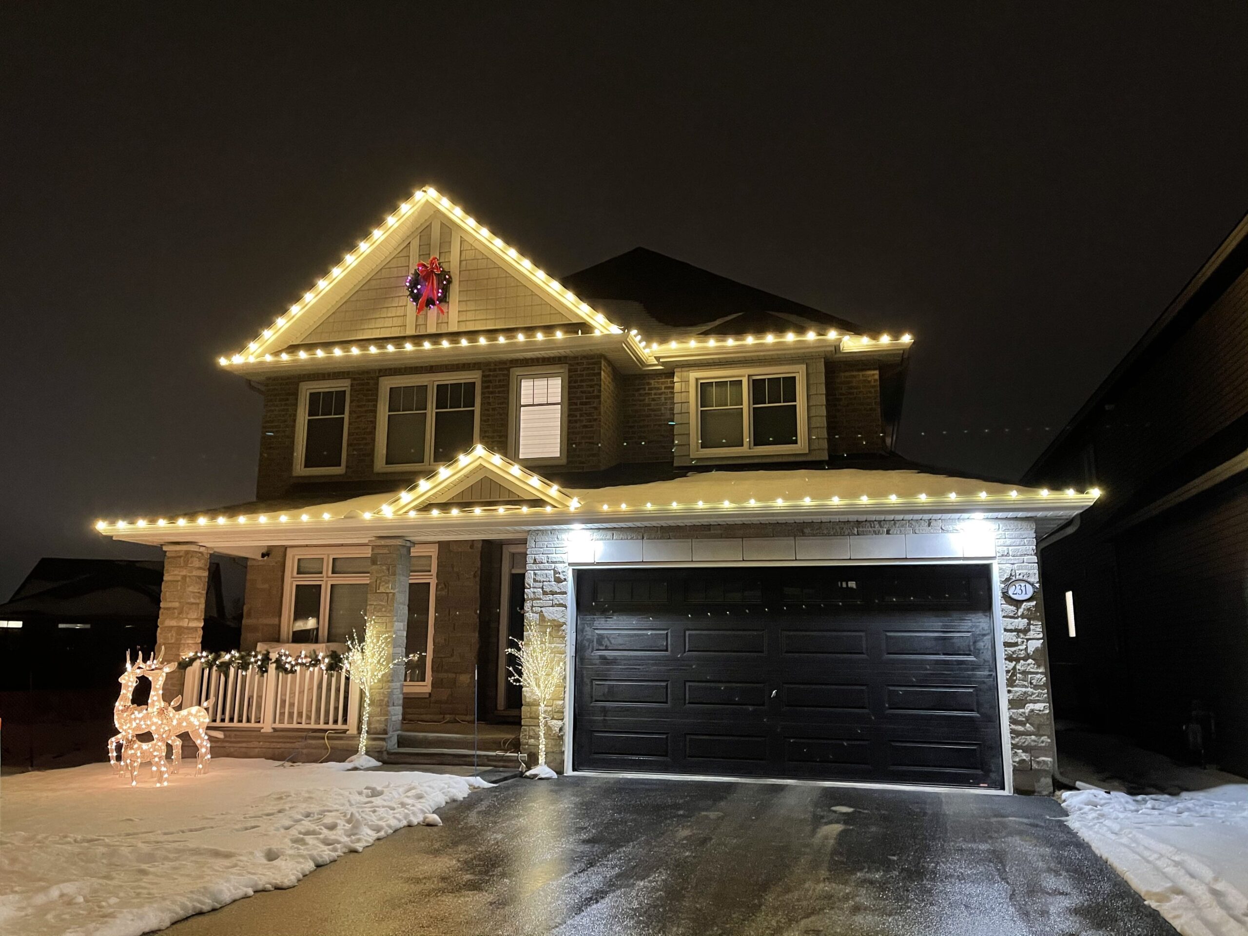 Two-story home with warm white lights along the garage roofline and gables