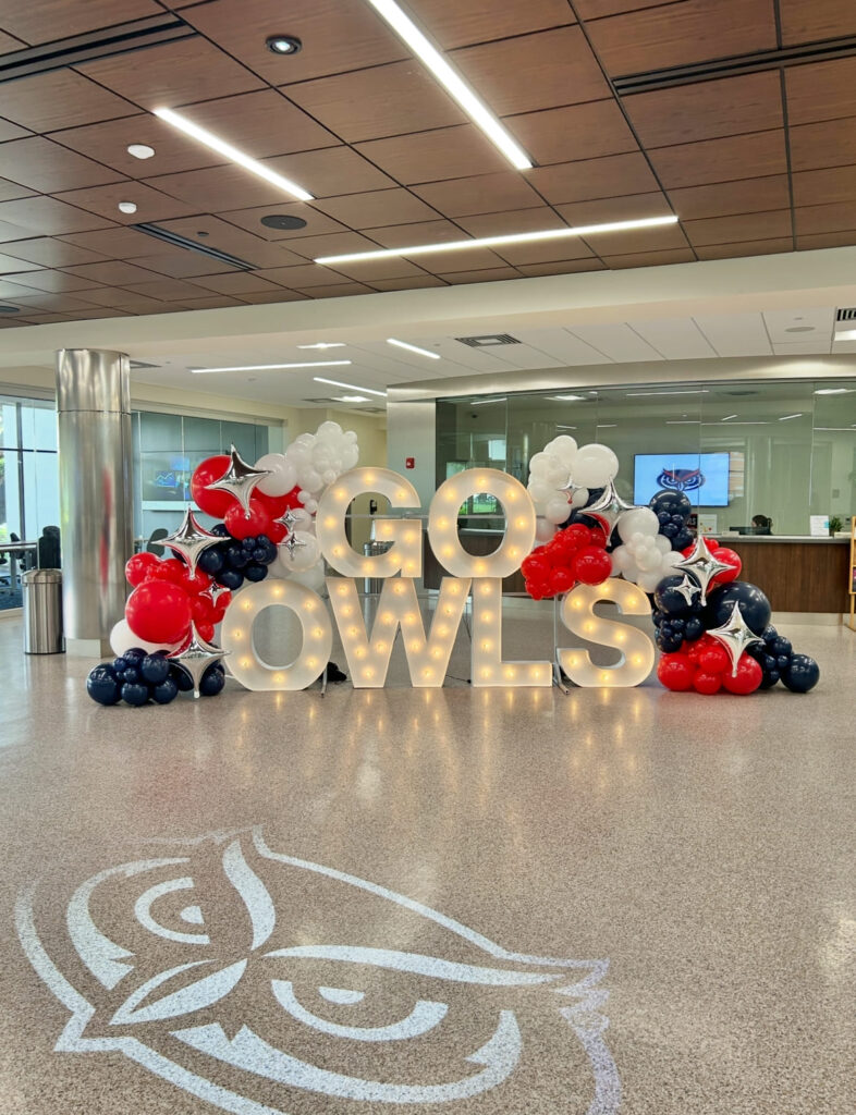 Light-up marquee letters framed by red, white and navy balloon garlands