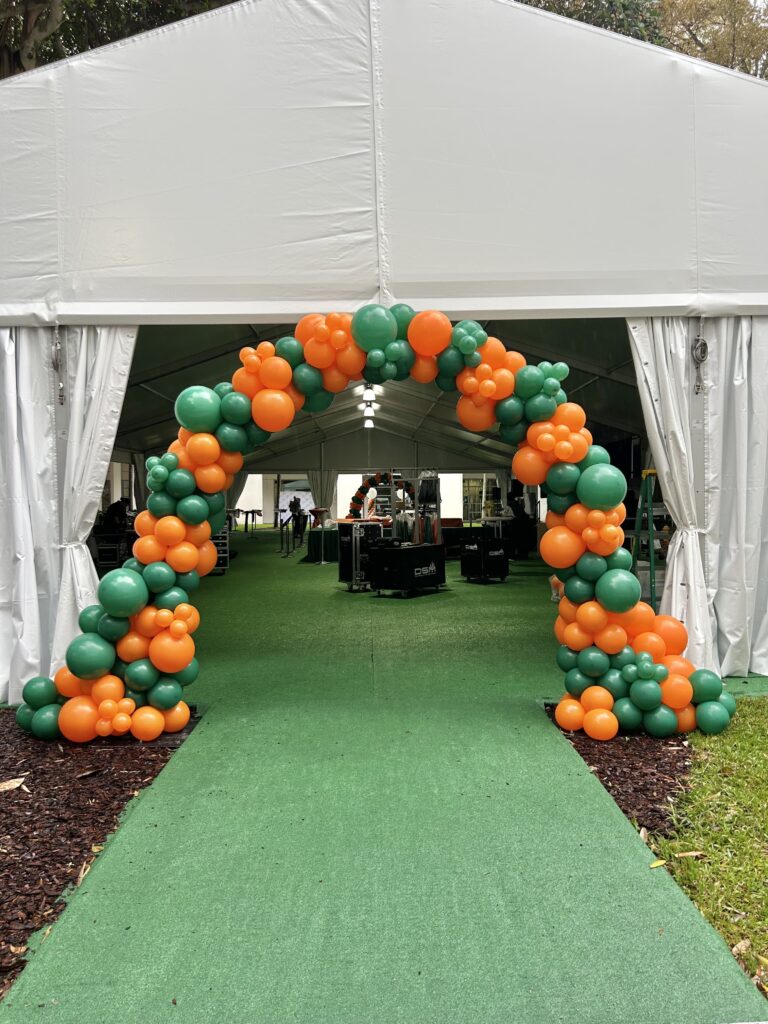 Orange and green balloon arch over a tent entrance